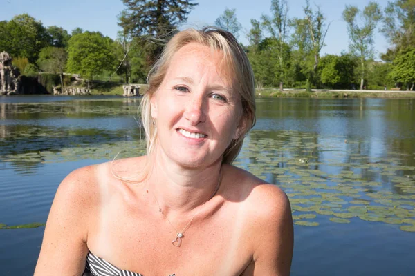 Bella donna occhi blu con i capelli biondi vicino al lago del parco in estate — Foto Stock