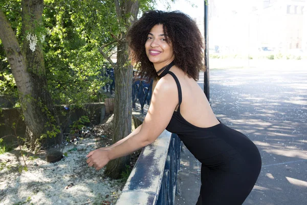 Beautiful woman with curly hair in a very sexy black dress in the city Stock Image