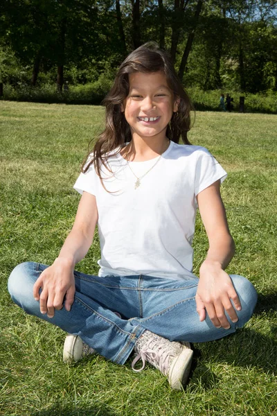 Bela menina jogando na grama fazendo ioga — Fotografia de Stock