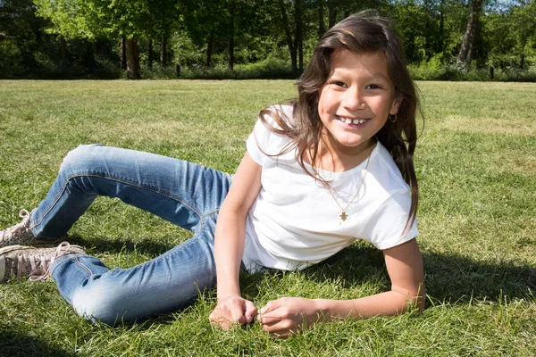 Menina bonita com cabelos longos deitado na grama verde — Fotografia de Stock