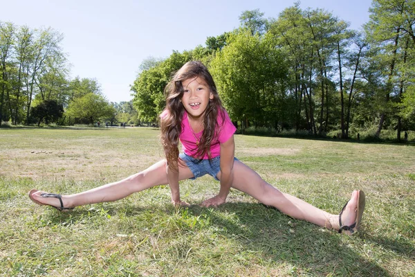 Menina criança joga para fazer ginástica no parque — Fotografia de Stock