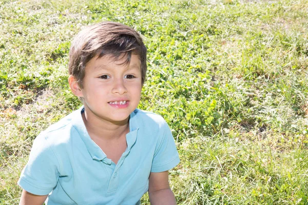 Niño sentado en la hierba en el jardín de la casa — Foto de Stock