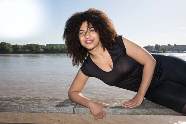 american mixed woman lying on the river bench in city