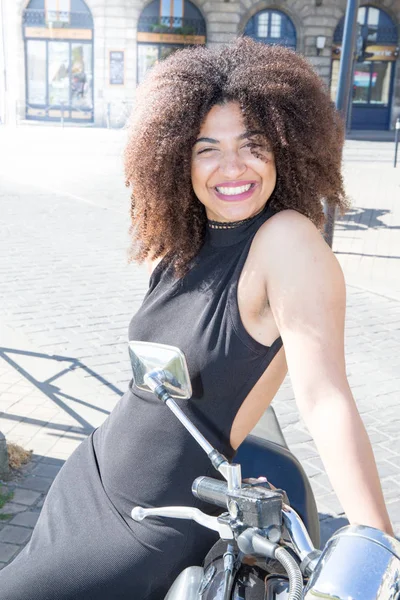 mixed woman smiling seating on a big motorcycle