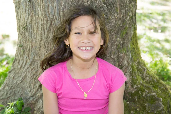 Menina bonita sorrindo no pé da árvore — Fotografia de Stock