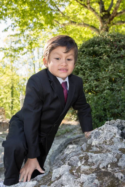 O menino sobe em uma rocha com seu traje — Fotografia de Stock