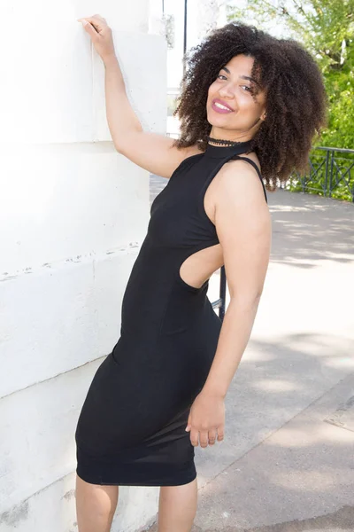 cheerful thin woman in a black dress with a cleavage in the back