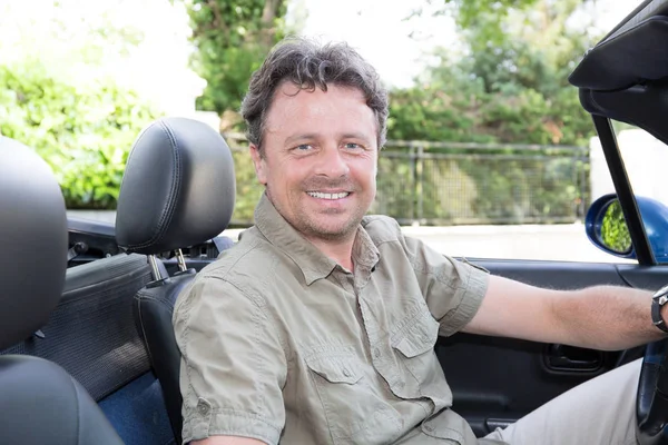 Middle-aged man sitting in a convertible car — Stock Photo, Image