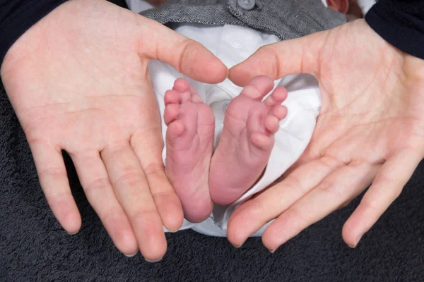 Hände Mutter formen ein Herz mit den Füßen des Neugeborenen — Stockfoto