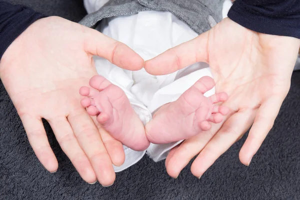 De handen van de moeder vorm een hart met de voeten van de pasgeborene — Stockfoto