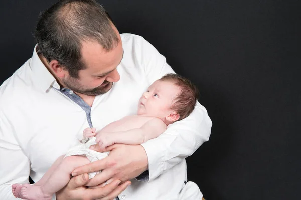 Padre mira a su bebé en sus brazos — Foto de Stock
