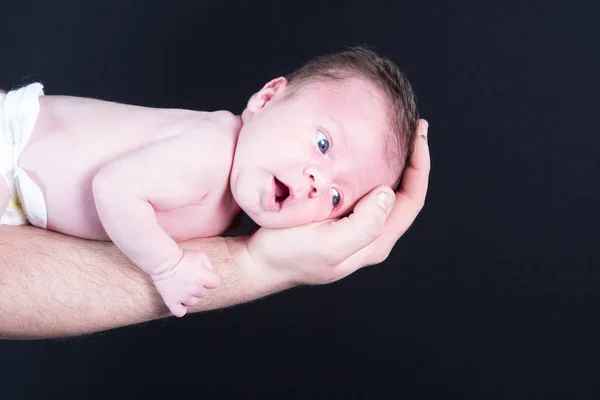 Hermoso bebé recién nacido acostado en el brazo de su padre con un fondo negro —  Fotos de Stock