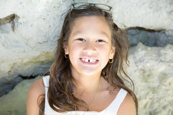 Pequena menina bronzeada ao ar livre com óculos no ombro — Fotografia de Stock