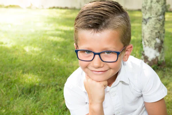 Kleiner zehnjähriger Junge mit Brille im hausgrünen Garten — Stockfoto