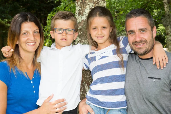 Família feliz sentado no banco no parque — Fotografia de Stock