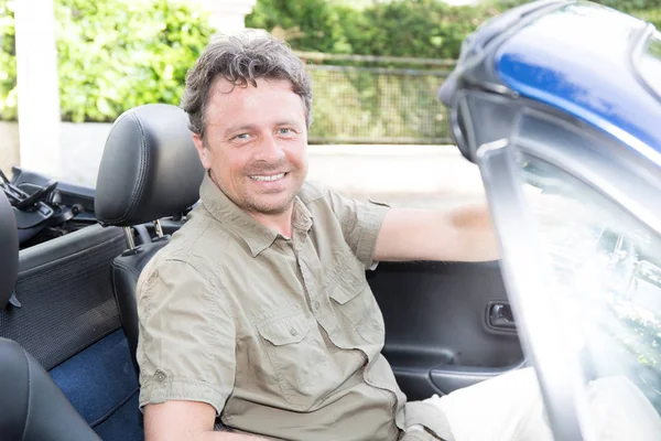 A beautiful smiling man sitting in his convertible car — Stock Photo, Image