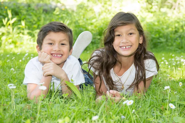 2 filhos irmão e irmã deitados na grama — Fotografia de Stock