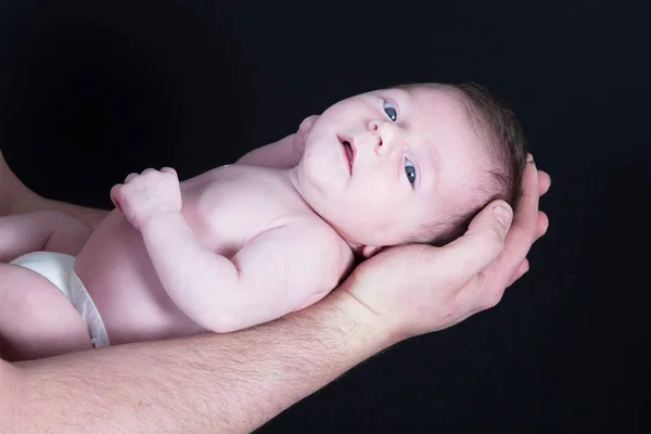 赤ちゃん生まれたばかりの子供を仰向けになって腕の父 ストック画像