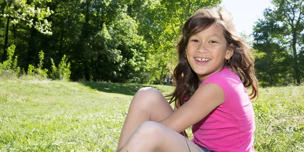 Leende glad flicka sitter på gräset trädgård park — Stockfoto