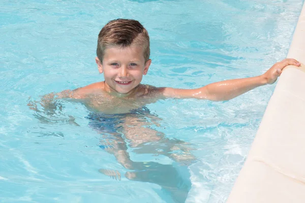 Hermoso niño pequeño se baña en la piscina del hotel —  Fotos de Stock