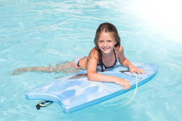 Chica joven jugando en la piscina con un pequeño bodyboard —  Fotos de Stock