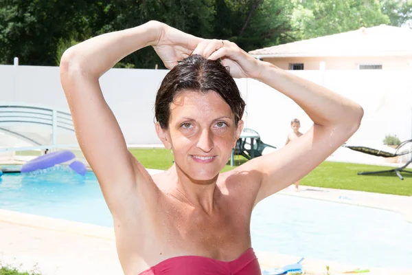 Kvinna binder håret vid kanten av sin egen pool — Stockfoto
