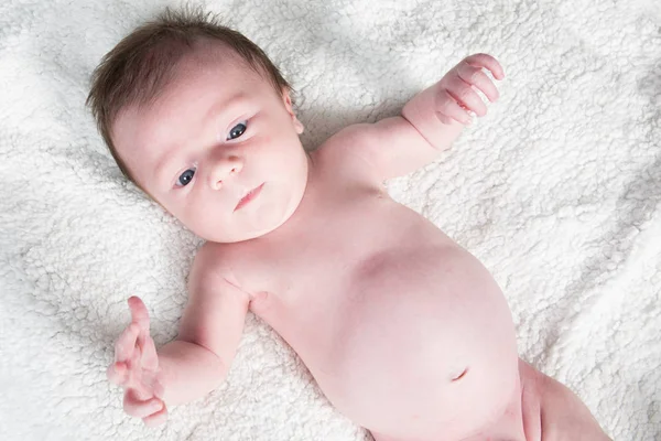 Beyaz yatakta mutlu sevimli yeni doğan bebek — Stok fotoğraf