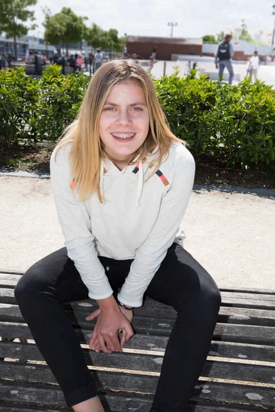 Tizenéves szőke lány ül a padon, a város — Stock Fotó