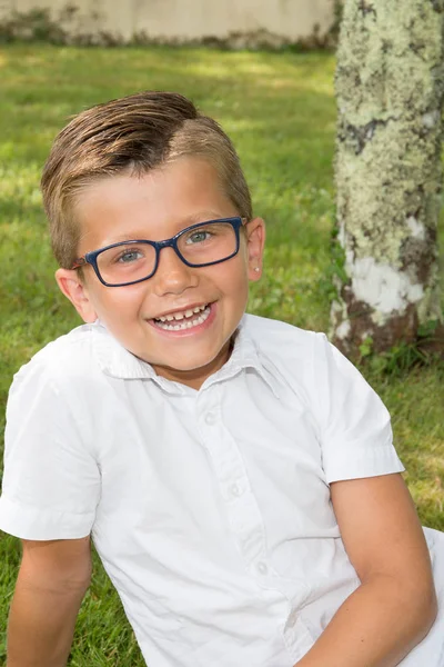 Sourire heureux jeune garçon assis sur l'herbe verte jardin parc — Photo