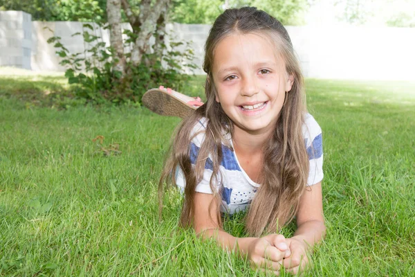 Glad ung flicka i trädgården liggande — Stockfoto