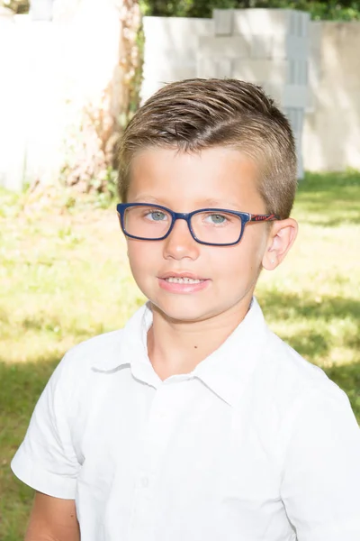 Mignon jeune garçon blond dans le jardin familial avec des lunettes — Photo