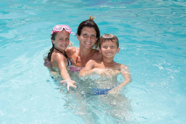 Bonita familia joven con madre y dos hijos en la piscina —  Fotos de Stock