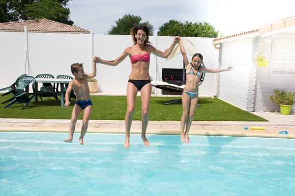 Feliz familia saltar en la piscina por diversión —  Fotos de Stock