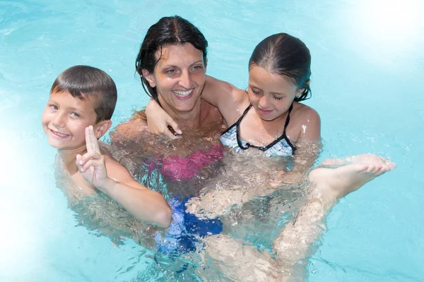 En vacaciones de verano madre con hijo hija en la piscina —  Fotos de Stock