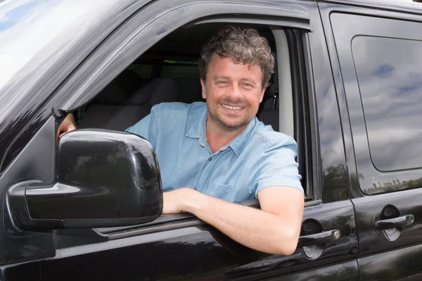 Guapo cuarenta hombre en furgoneta negra con sonrisa — Foto de Stock