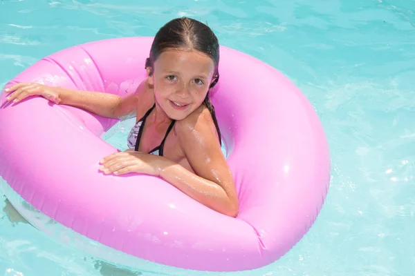 Niña bonita en la piscina con boya rosa en la piscina en la casa del jardín —  Fotos de Stock