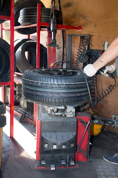 Man mechanic changes the tire of a car wheel — Stock Photo, Image