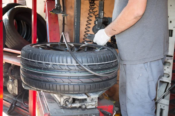Técnico especialista muda pneu do carro com sua máquina — Fotografia de Stock