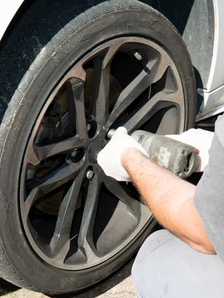 A man changing wheels of white car — Stock Photo, Image