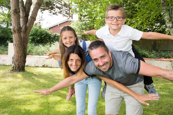 Família piggyback no jardim casa verão — Fotografia de Stock