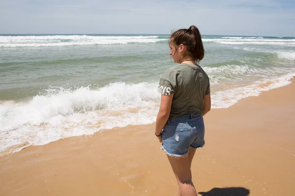 Bakifrån flicka ensam på stranden sommardag — Stockfoto