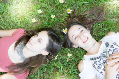Eğlenceli kızlar ikiz kız kardeşler genç çimen çiçekler üzerinde yalan