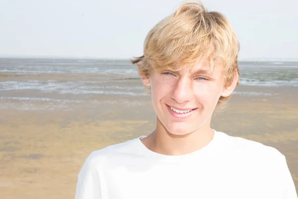 young blond man smiling in sunny day on beach