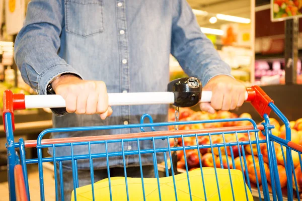 man pushes a trolley in a supermarket at the fruit and vegetables department