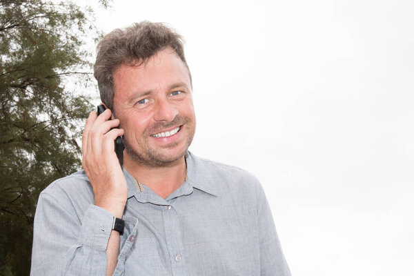 Young business man calling by cell phone outdoors on white beach