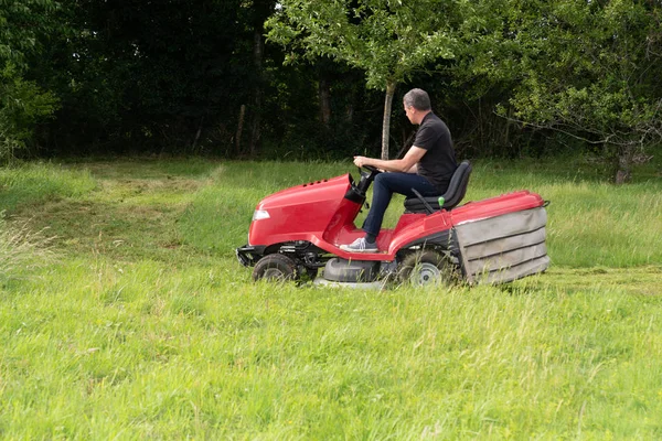 Férfi Kertész Vezetés Piros Modern Traktor Lovaglás Fűnyíró Zöld Kertben — Stock Fotó