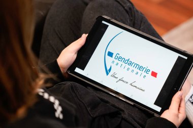Bordeaux , Aquitaine / France - 11 30 2019 : gendarmerie french police sign logo screen tablet hands young woman in home sofa France clipart