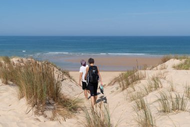 two women walking sand dune beach go to ocean atlantic sea in cap Ferret France clipart