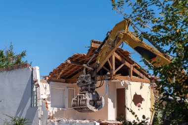 İnşaat alanı kazıcısı sarı yıkım evi yeniden inşa etmek için