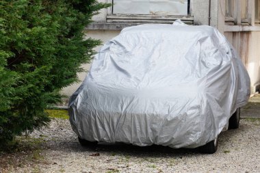 Ev bahçesinde koruma gümüşü ile park edilmiş bir araba.